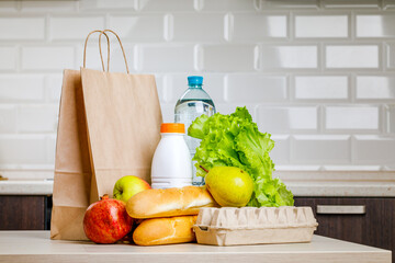 Secure home delivery. A box with various products such as milk, fruit and bread in the kitchen