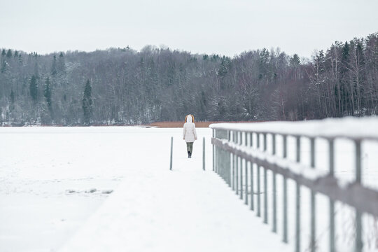 Woman In White Walking On Frozen Lake In Winter In Finland.