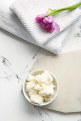 Bowl with shea butter and towels on white background