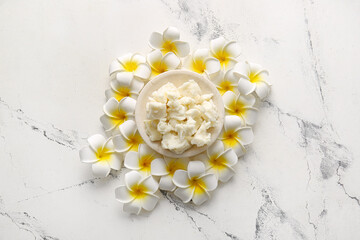 Plate with shea butter and flowers on white background