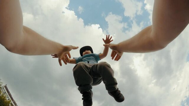 Caring father hands tossing up funny little son having fun and positive emotion POV shot blue sky