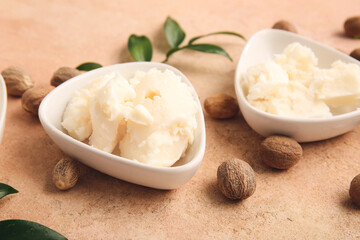 Bowls with shea butter on color background