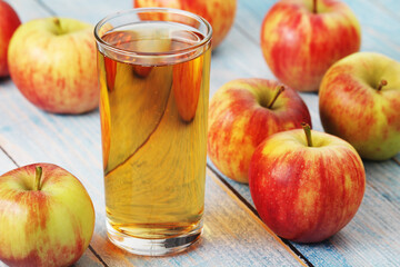 A glass with apple juice and ripe apples