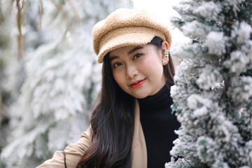 Portrait of young beautiful woman in winter clothes. while posing on snow background. Outdoor close-up photo of female model with romantic smile chilling in park in winter.