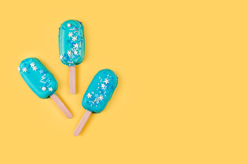 Blue mint ice cream popsicles on yellow background. Tasty and refreshing ice cream on sticks. Minimal summer concept. Flat lay, copyspace for text.