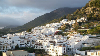 Fototapeta na wymiar White houses during sunset in Nerja Village, located within a green hill landscape in Andalusia, Spain.