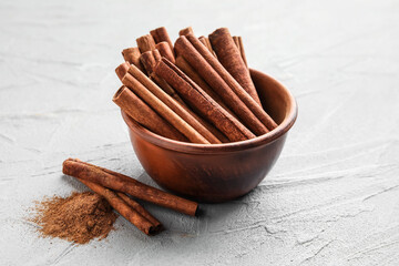 Cinnamon sticks in bowl on grey background