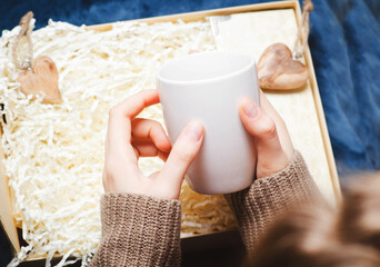 Valentines day concept. female hands holding a white cup from a gift box.
