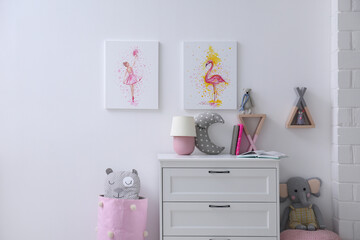 Chest of drawers and beautiful pictures in children's room. Interior design