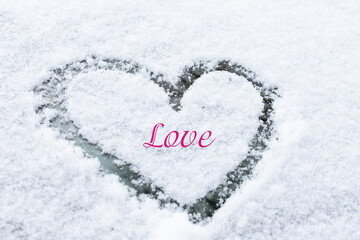 Symbol of heart on the background of fresh snow texture .Valentine's Day Concept. Copy space.Finger-drawn heart on the snow-covered windshield of a car.Love concept.Creative Valentine's Day