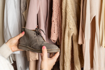 Woman choosing boots (shoes) and clothes in home cupboard. Season concept