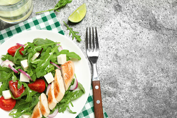 Delicious salad with meat, arugula and vegetables on grey table, flat lay. Space for text