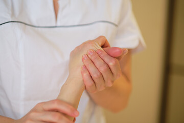 Wrist massage. massage therapist puts pressure on a sensitive point on a woman's hand. Physiotherapist massaging her patients hand in medical office