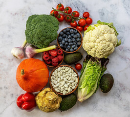 Healthy food background, trendy plant based diet products - fresh raw vegetables, berries, and beans.