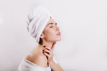 Charming girl without make-up gently massages her neck. Woman with perfect skin posing on white background