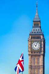 Fototapeta na wymiar British Icons Backdrop / Famous London city clock tower and union jack flag detail at blue sky background for your text (copy space)