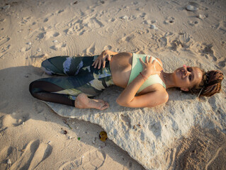 Yoga on the beach. Beautiful woman lying on the sand, practicing Supta Virasana Reclining Hero...