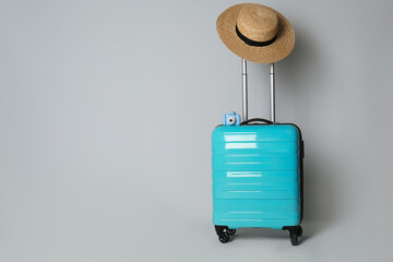 Travel suitcase with hat and camera on light grey background, space for text. Summer vacation