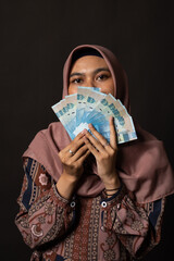 Happy young woman with cash money on black background