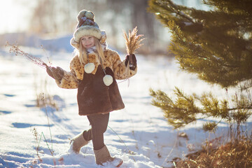 little girl in a fur coat playing with snow