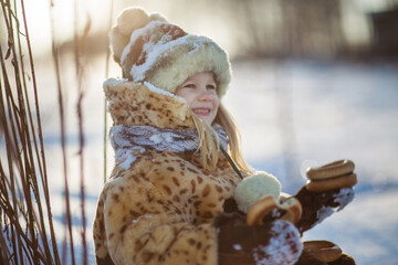little girl in a fur coat playing with snow