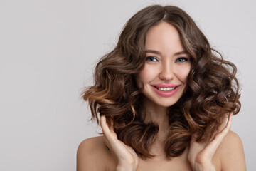 Happy young beautiful woman with curly hair. grey background