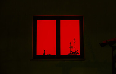 red light from the window. the red window shines mystically at night. mysterious red window