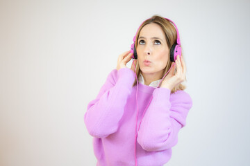 Pretty young woman listens and enjoys the music in headphones over white background.