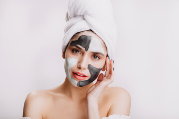 Girl uses white and black clay to improve and cleanse skin. Portrait of model in towel after washing her hair