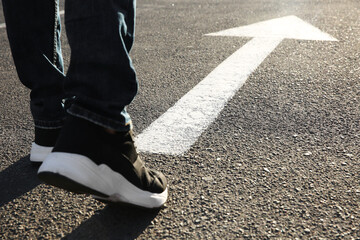 Man going along road with arrow marking, closeup