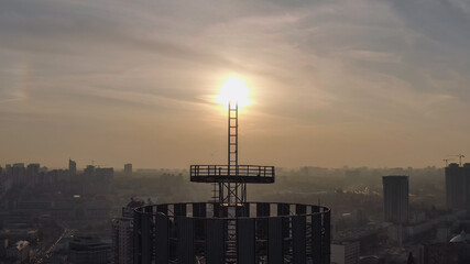 silhouette of a roof spire, lightning rod in a skyscraper. against the backdrop of sunset and evening city center