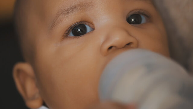 Close up, dark skin baby drinking his baby milk from the bottle. High quality photo