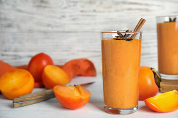 Tasty persimmon smoothie with anise and cinnamon on white wooden table. Space for text