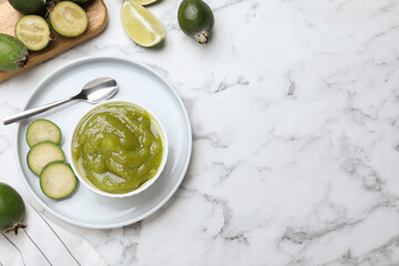 Feijoa jam and fresh fruits on white marble table, flat lay. Space for text