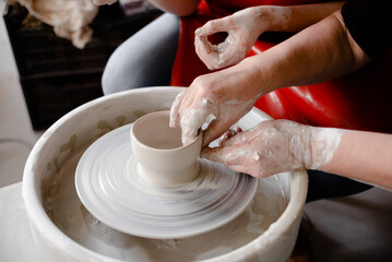 Female hands crafting a pottery cup on a potter's wheel. Handmade and crafting concept.
