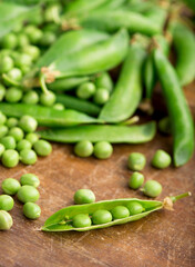 RAW baby peas in small white bowl, over retro wooden boards. Close-up.