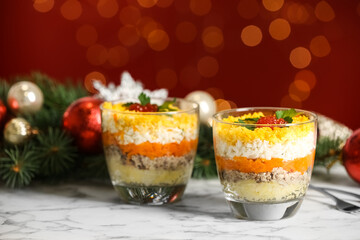 Traditional russian salad Mimosa and festive decor on table against blurred lights