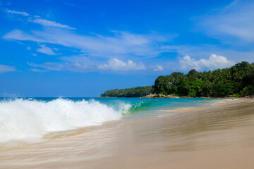 Sea waves on the sand beach in the tourist season and blue sky background at surin beach island Phuket Thailand