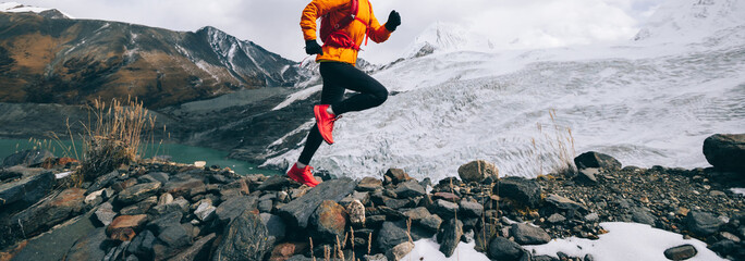 Woman trail runner cross country running up to winter snow mountain top