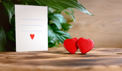 Pair of red hearts on wooden rustic background and Valentine's Day greeting card. Concept for valentine's day, wedding, family happiness, world heart day, love, family. Copy space for text