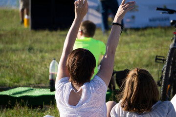 Obraz premium Two girls running hand-in-hand on green meadow with dandelions symbolizing a happy friendship and freedom, back visible.