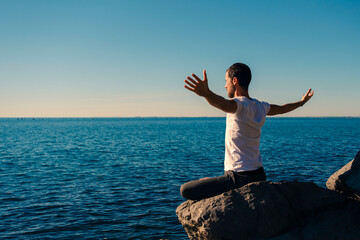 Attractive young man practicing yoga meditation and breathwork outdoors by the sea