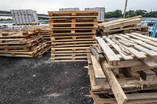 Pile of wooden pellets, some damaged, ready for recycling, stacked on a construction site of a warehouse, used for shipping and transportation of cargo and material