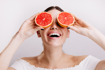 Portrait of girl with snow-white smile without makeup on isolated background. Young woman posing with mask of grapefruits