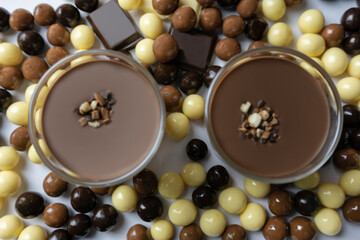 Top view of two Chocolate dessert in glass (yogurt or cream, cookies and nuts )with chocolate balls (black chocolate, milk chocolate and white chocolate ). Sweet dessert concept.