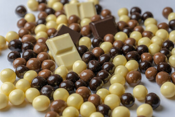 Delicious chocolate balls candies (black chocolate, milk chocolate and white chocolate ) with chocolate pieces on white background.