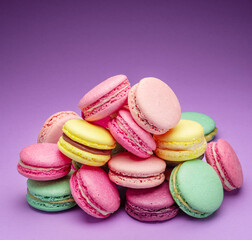 Colorful sweet macarons or macaroons, flavored cookies on purple background.
