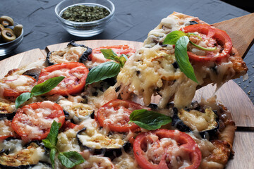 Pizza with eggplant ,olives and mushroom. Italian cuisine. Ingredients for making pizza on a black background.Top view.Concept for advertising restaurants or pizzerias.