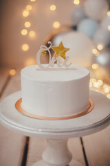 White cake in a stylish photo zone with a topper with the inscription one.