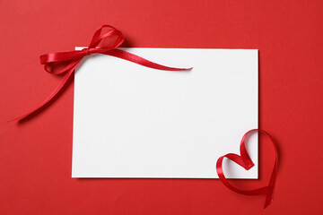 Blank card and ribbons on red background, flat lay with space for text. Valentine's Day celebration